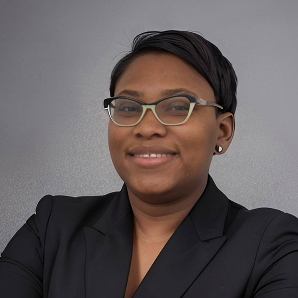A professional headshot of Ingrid Clark, NDIT Technology Outreach Apprentice, wearing glasses and her black blazer.